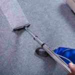 Man in blue uniform vacuuming carpet with a vacuum cleaner