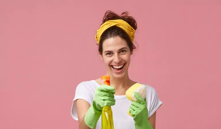 young woman holding a cleaning spray and a sponge in her hands