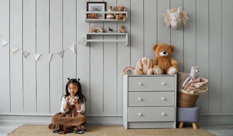 Cute child is playing with her toy inside a kid room.
