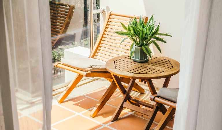 A flower pot on the patio furniture in the balcony of a home.