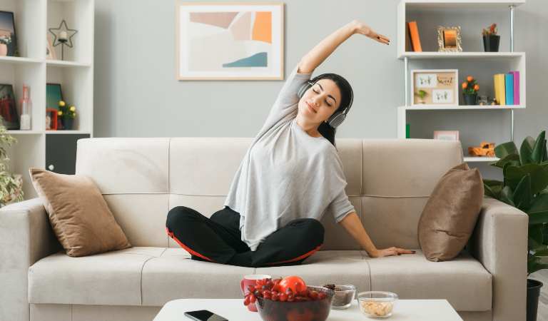 Woman on sofa listening music in her headphone.