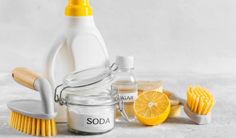 White bottle, baking soda, lemon and brush on the table
