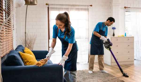 Young man and woman cleaning service worker work in living room housekeeper cleaner team wear apron and cleaning messy dirty floor for housekeeping housework