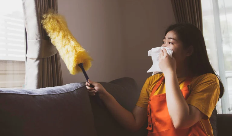 Asian woman doing housework dusting dirty window blinds covering her nose