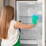 Woman cleaning empty refrigerator in kitchen