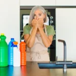 Middle age woman looking worried, cleaning supplies on the surface