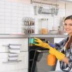 Young woman cleaning oven in kitchen