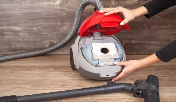 Girl showing dust bag in a vacuum cleaner