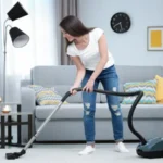 Woman cleaning carpet with vacuum in living room
