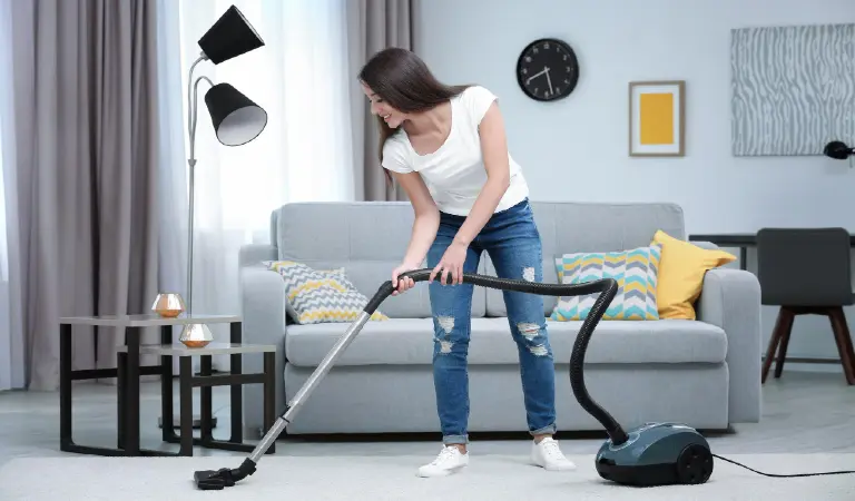 Woman cleaning carpet with vacuum in living room