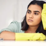 Woman sad and spray bottle on counter for cleaning tired and chemical product or detergent female person burnout