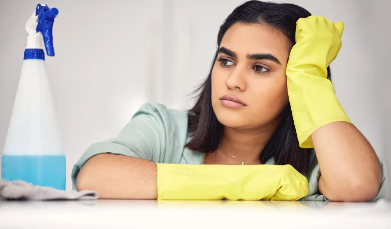 Woman sad and spray bottle on counter for cleaning tired and chemical product or detergent female person burnout