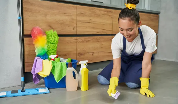 Making home look best cheerful young woman cleaning floor with detergents at home