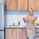 Young woman cleaning kitchen cabinets